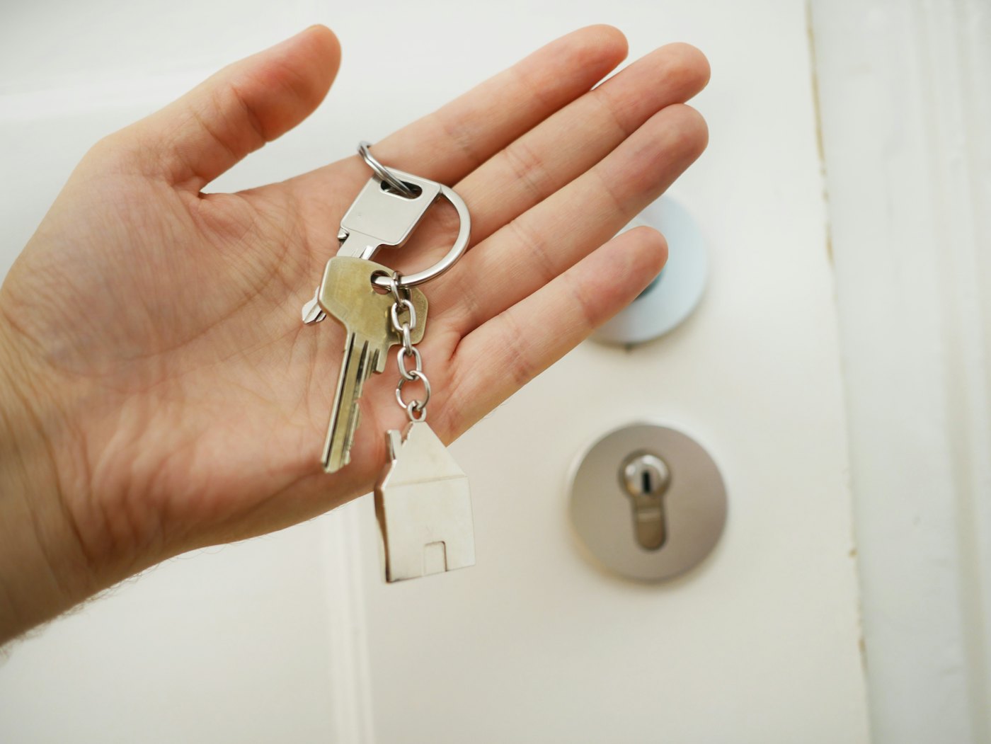 House keys held near a front door for a mortgage and home cost article